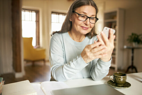 woman wearing glasses looking at her phone 